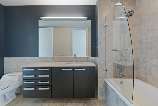 a bathroom with a granite countertop sink a toilet and bathtub