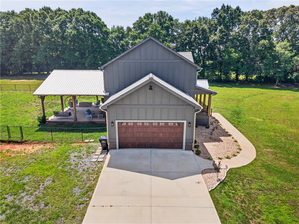 5016 Copeland Road Belton, SC 29627 - Photo 43 of 45 A striking gray residence with a welcoming covered patio and attached garage, nestled among mature trees and open green spaces.