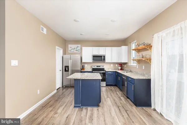 a kitchen with stainless steel appliances granite countertop a refrigerator a stove top oven a sink dishwasher and wooden floor
