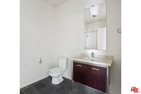 a bathroom with a granite countertop toilet a sink and a mirror