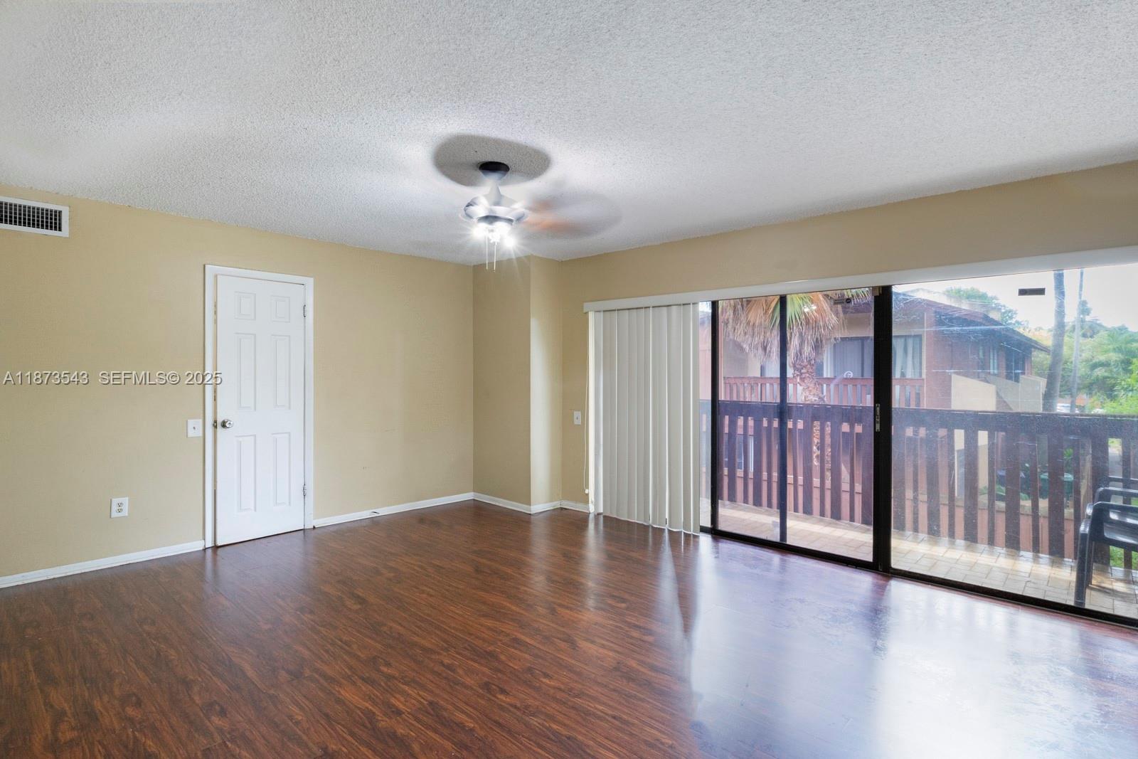 6924 Southwest 114th Place, Unit H56 Miami, FL 33173 - Photo 13 of 19 a view of an empty room with wooden floor and windows