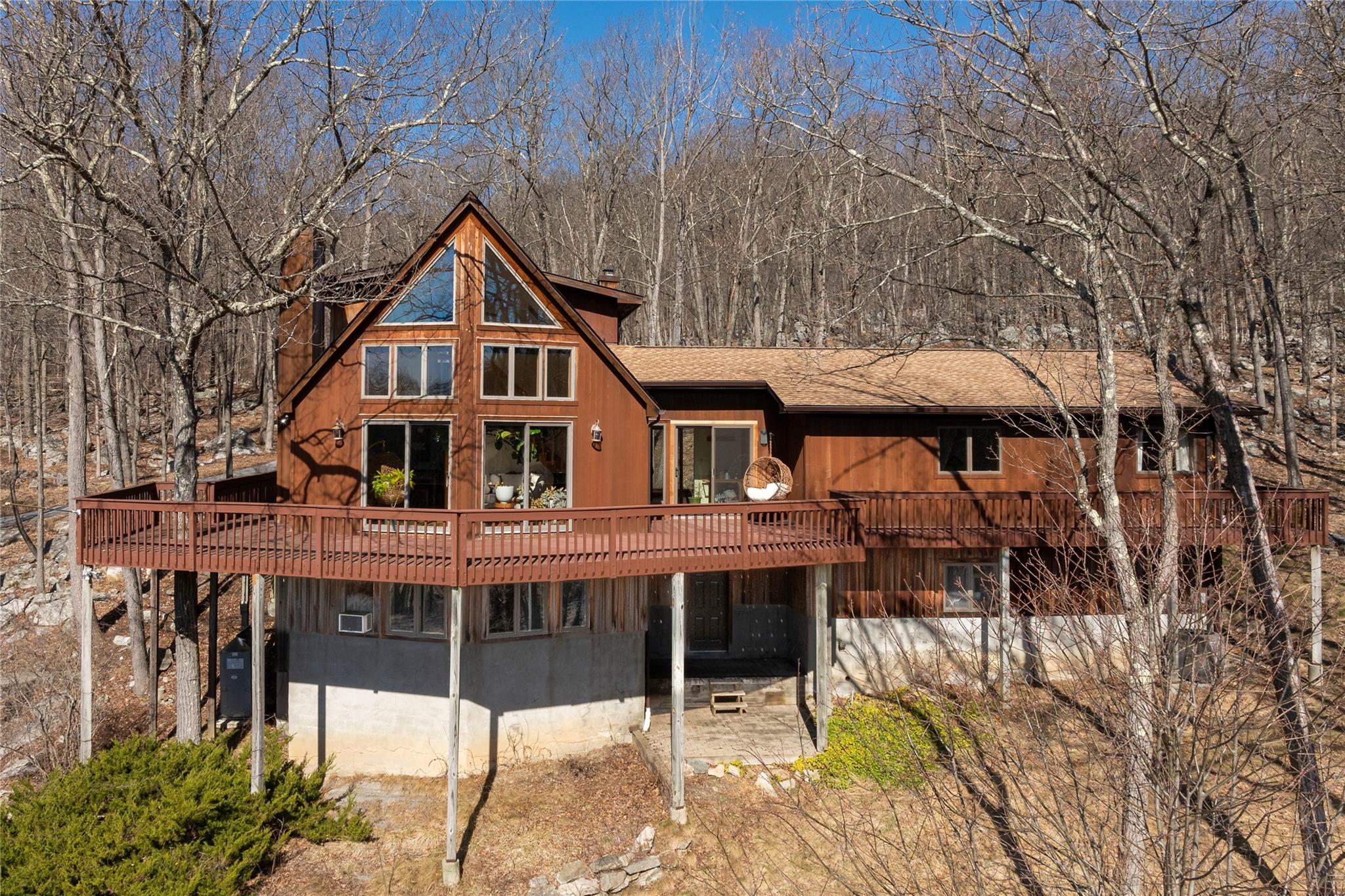Rear view of house featuring a shingled roof, a chimney, and a wooden deck