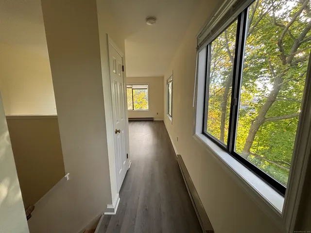 a view of hallway with a large window and wooden floor