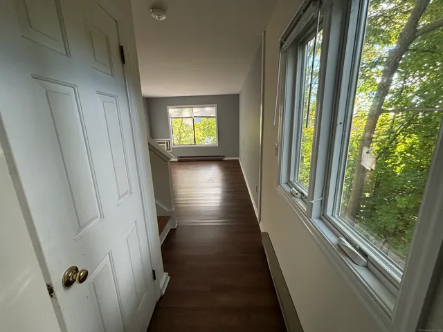 a view of a hallway with wooden floor and stairs