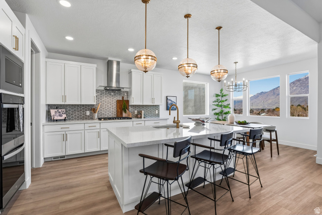 624 North Legend Circle, Unit 480 Mapleton, UT 84664 - Photo 15 of 34 Kitchen featuring a mountain view, white cabinetry, a kitchen bar, an island with sink, and light stone counters