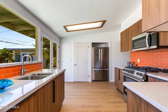 a kitchen with stainless steel appliances a stove a refrigerator a sink and wooden floor