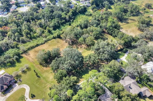 an aerial view of residential house with outdoor space and trees all around