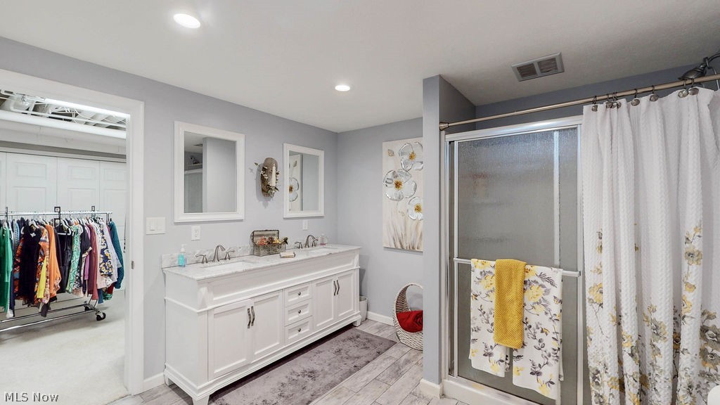 36845 Aberdeen Lane Solon, OH 44139 - Photo 19 of 24 Bathroom in lower level with a stall shower, double vanity, a walk in closet, light wood-style floors, and recessed lighting