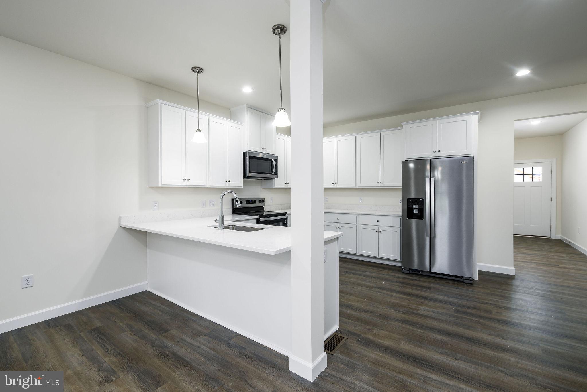 5 Valhalla Court Dover, DE 19904 - Photo 21 of 53 a kitchen with wooden floor white cabinets and stainless steel appliances