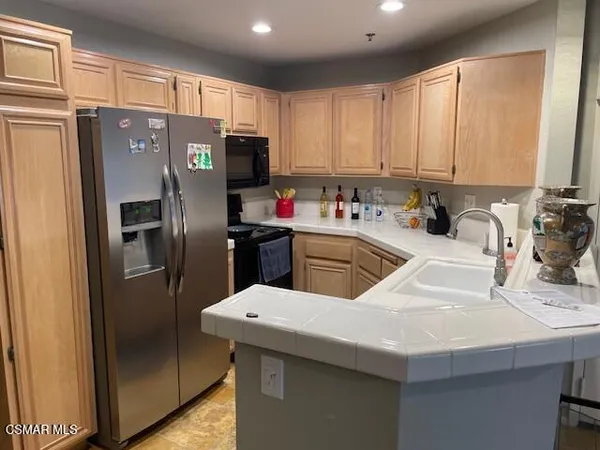 a kitchen with stainless steel appliances a sink a refrigerator a stove a microwave and island