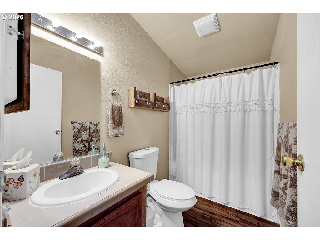 35235 Row River Road Cottage Grove, OR 97424 - Photo 20 of 28 a bathroom with a sink a toilet a mirror and shower curtain