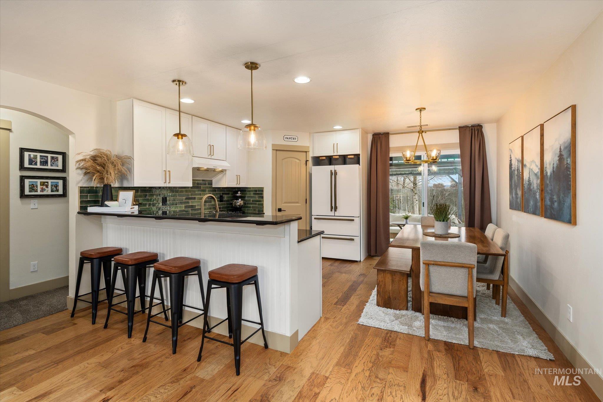 1065 West 11th Street Weiser, ID 83672 - Photo 16 of 48 Kitchen with white cabinets, a breakfast bar area, freestanding refrigerator, suspended lighting, and a peninsula