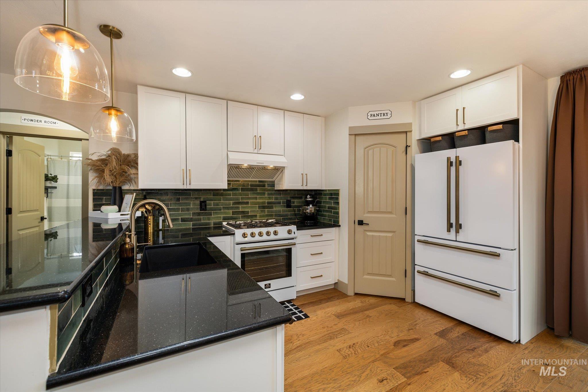 1065 West 11th Street Weiser, ID 83672 - Photo 20 of 48 Kitchen with white appliances, dark stone counters, white cabinets, and light wood-style floors