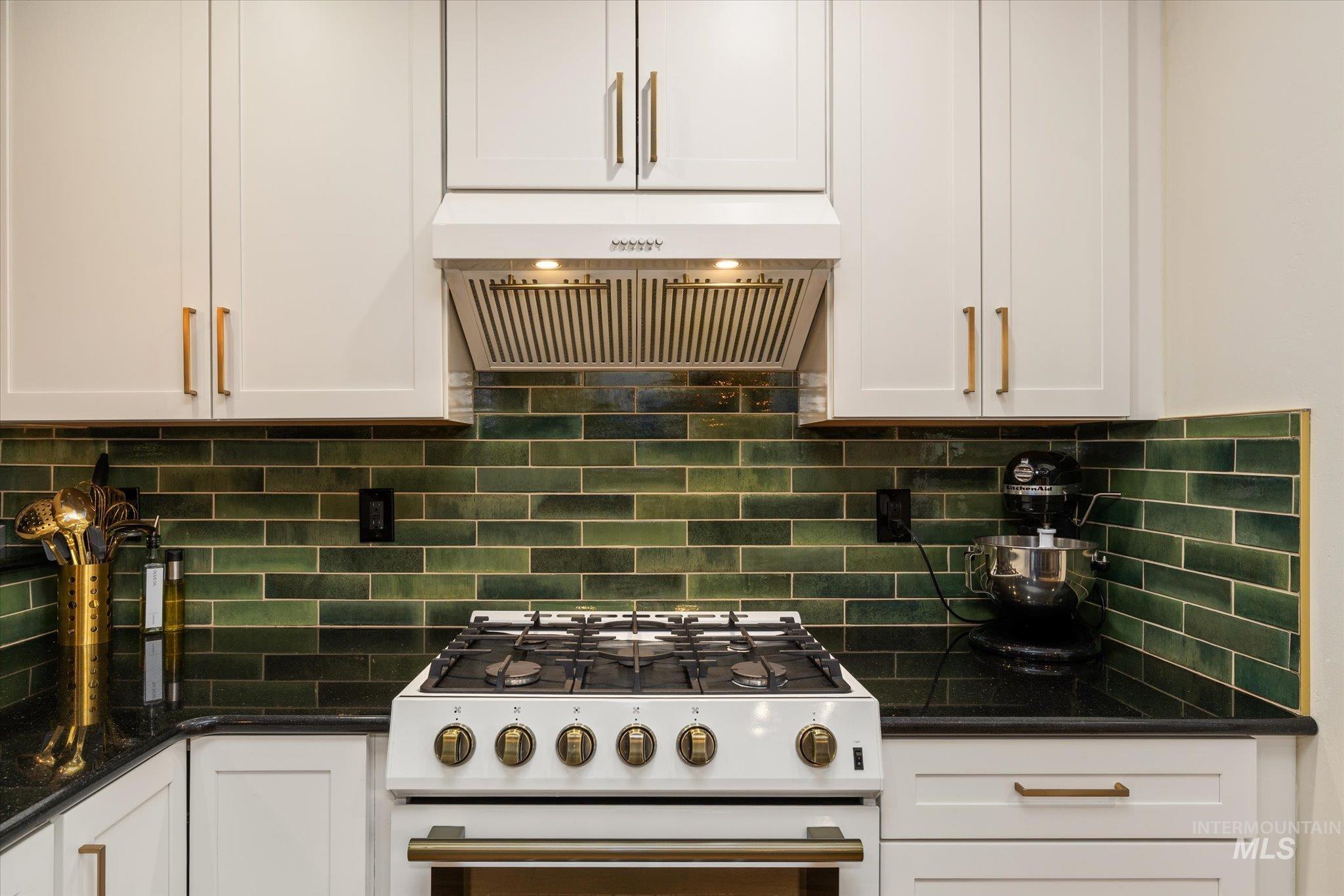1065 West 11th Street Weiser, ID 83672 - Photo 22 of 48 Kitchen featuring high end stove, dark stone counters, white cabinets, extractor fan, and decorative backsplash