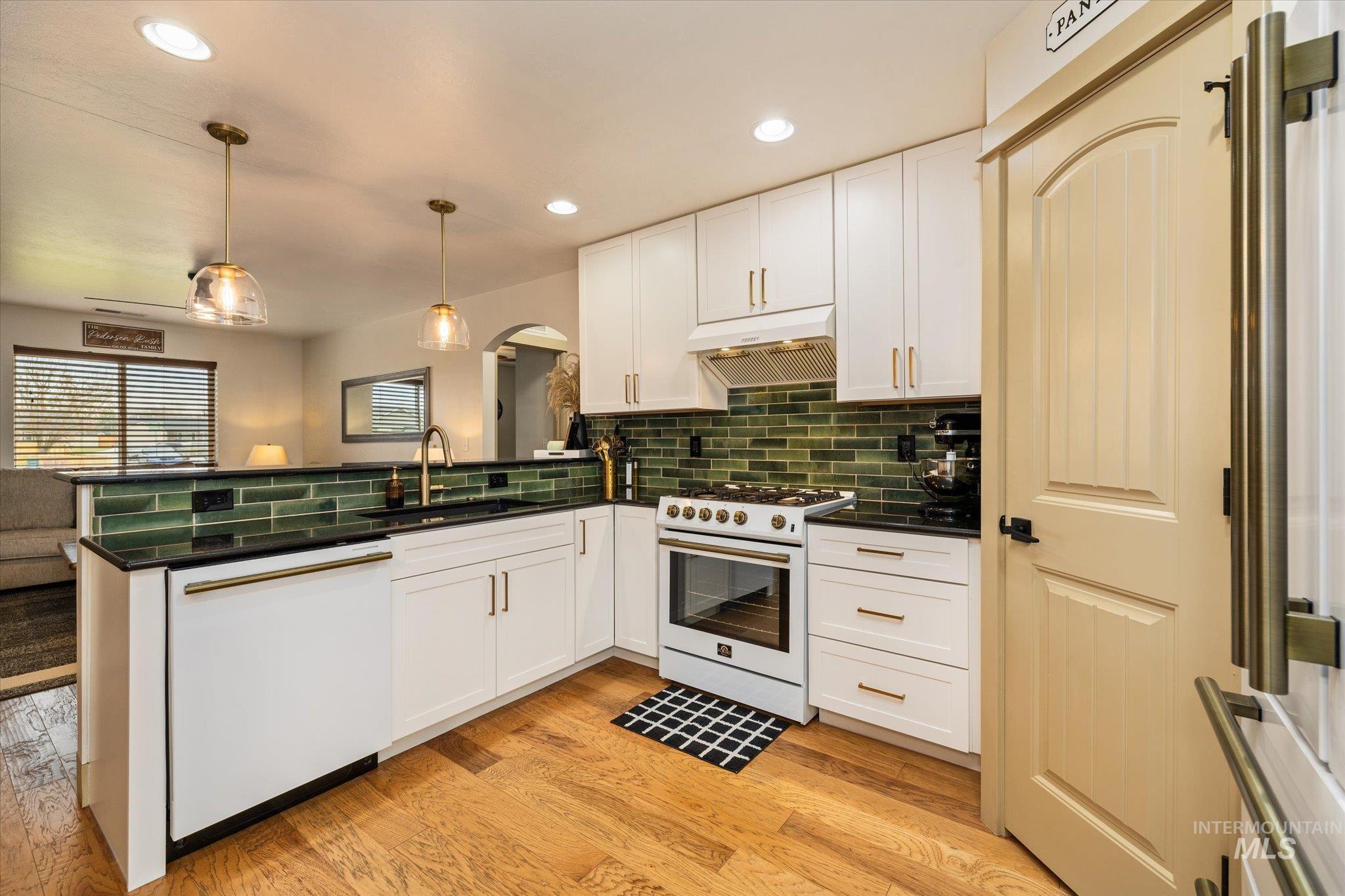 1065 West 11th Street Weiser, ID 83672 - Photo 24 of 48 Kitchen with a peninsula, gas range oven, dishwasher, light wood-style floors, and white cabinets