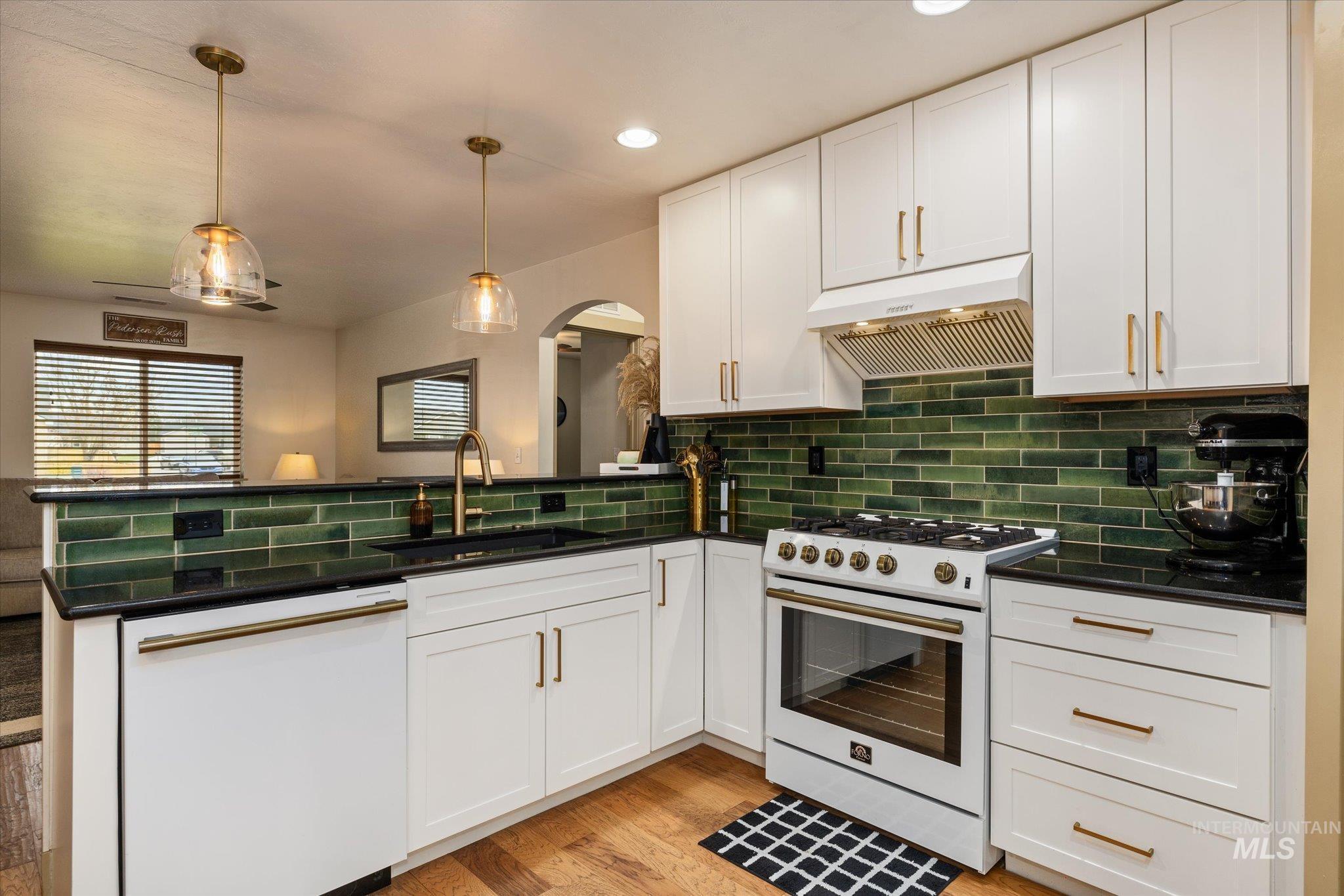 1065 West 11th Street Weiser, ID 83672 - Photo 27 of 48 Kitchen with white appliances, white cabinetry, a peninsula, hanging light fixtures, and light wood-style flooring