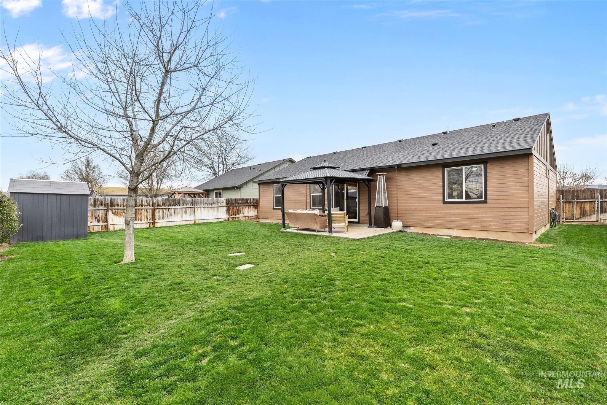 1065 West 11th Street Weiser, ID 83672 - Photo 6 of 48 Back of house featuring a gazebo, a patio, a shed, a fenced backyard, and roof with shingles