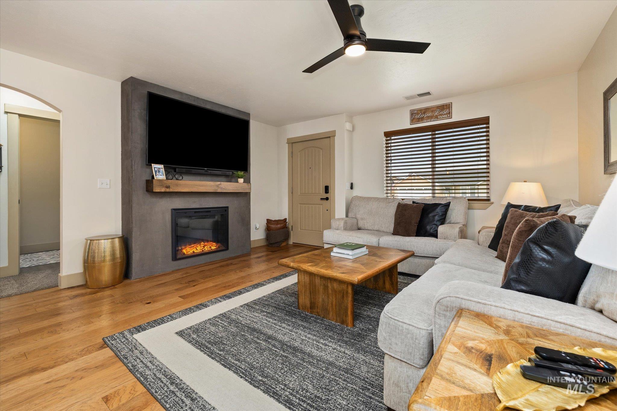 1065 West 11th Street Weiser, ID 83672 - Photo 10 of 48 Living area featuring wood finished floors, a ceiling fan, a large fireplace, and arched walkways