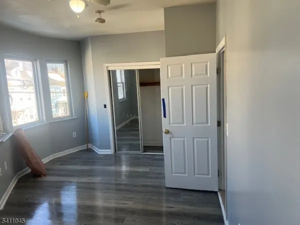 an empty room with wooden floor closet and windows