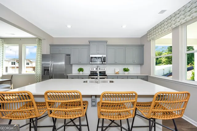 a kitchen with stainless steel appliances granite countertop a dining table chairs and a refrigerator