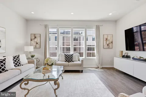 a open kitchen with stainless steel appliances kitchen island granite countertop a stove a sink a refrigerator and white cabinets with wooden floor