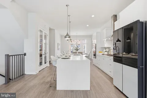 a kitchen with stainless steel appliances granite countertop a stove a sink dishwasher and white cabinets with wooden floor