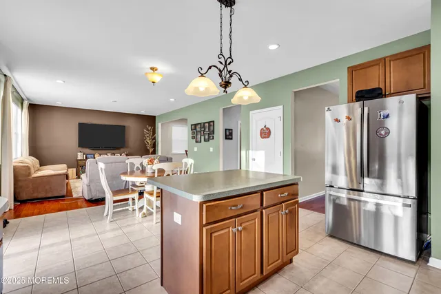 a kitchen with stainless steel appliances granite countertop a refrigerator a sink dishwasher a dining table and chairs with wooden floor