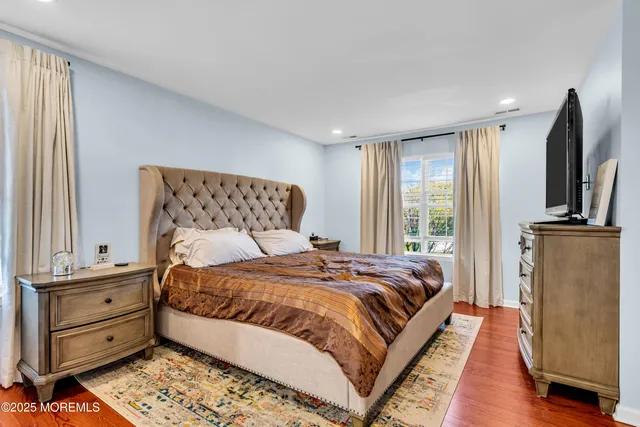 a bedroom with a bed and a dresser with wooden floor