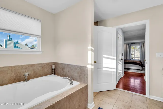 a bathroom with a tub a sink and wooden floor