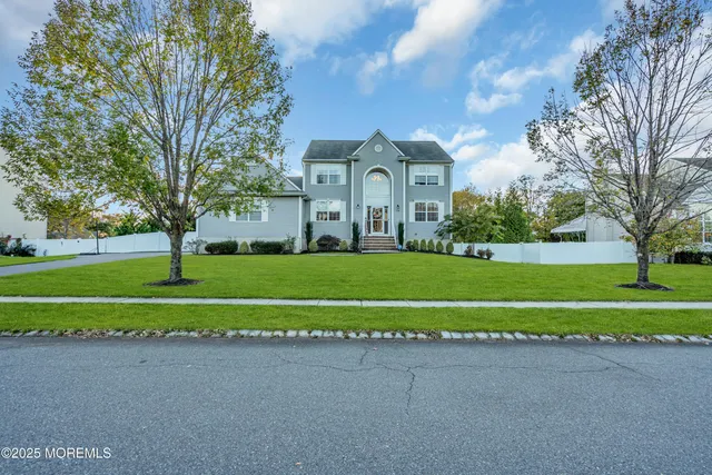 a view of a house with a big yard and potted plants and large trees