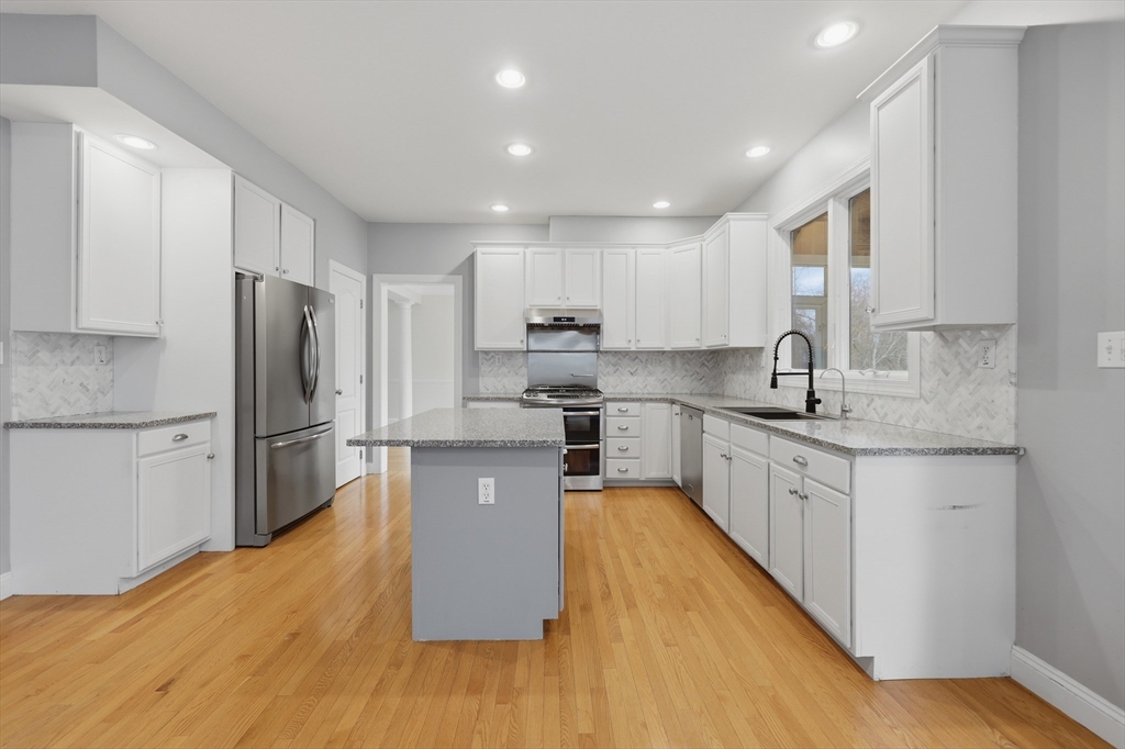 35 Peter Street Holliston, MA 01746 - Photo 11 of 42 a large kitchen with stainless steel appliances granite countertop a refrigerator a stove top oven a sink and cabinets