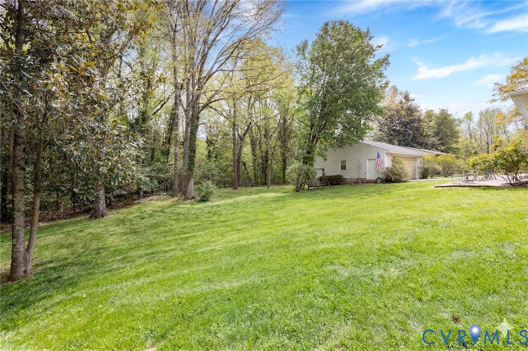 7035 Conifer Road Richmond, VA 23237 - Photo 36 of 38 View of green lawn with a garage and view of woode