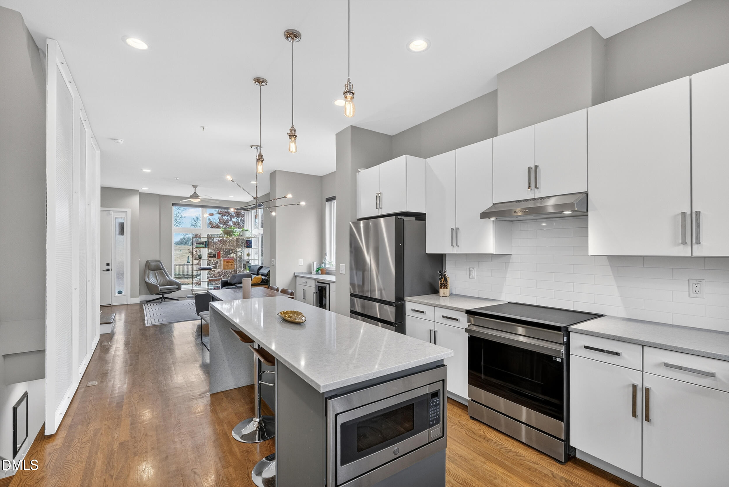 537 New Bern Avenue, Unit 101 Raleigh, NC 27601 - Photo 11 of 34 a kitchen with stainless steel appliances a stove a sink a refrigerator and white cabinets with wooden floor