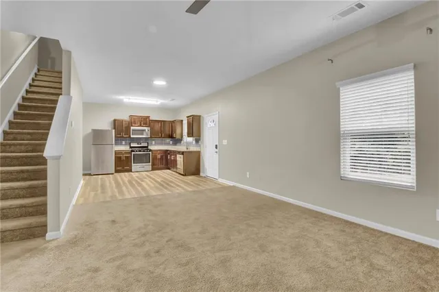 a view of kitchen and empty room with wooden floor