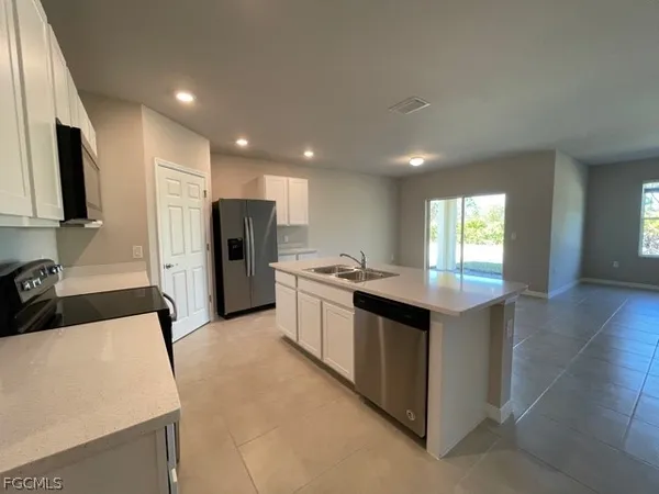 a kitchen with stainless steel appliances granite countertop a refrigerator a sink dishwasher and a stove with wooden floor