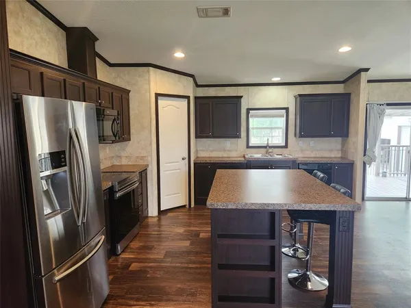 a view of kitchen with stainless steel appliances granite countertop a stove top oven a sink dishwasher and a refrigerator with wooden floor