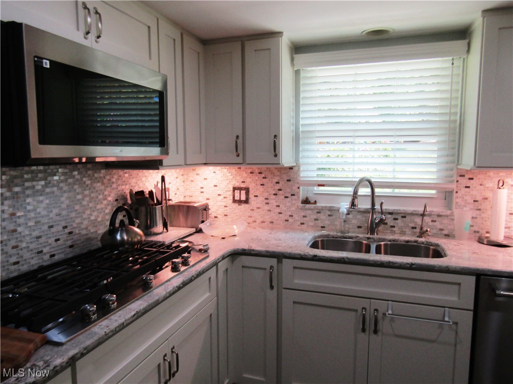2970 Culler Road Weirton, WV 26062 - Photo 9 of 34 Kitchen with backsplash, stainless steel appliances, light stone countertops, and sink