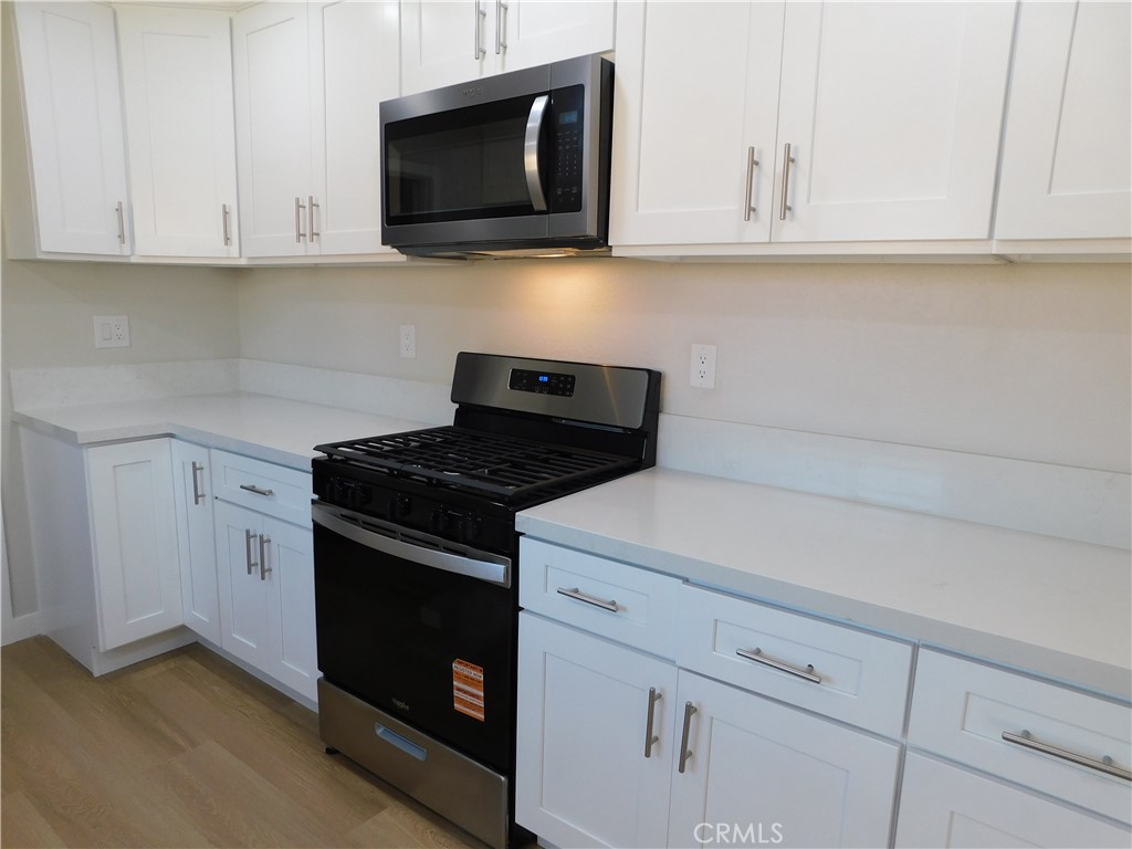 10456 Napa Road Adelanto, CA 92301 - Photo 12 of 31 a kitchen with white cabinets and black appliances