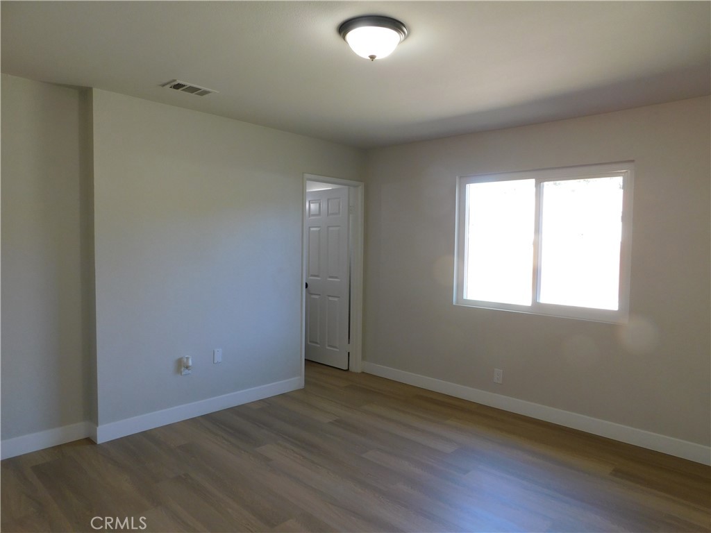 10456 Napa Road Adelanto, CA 92301 - Photo 19 of 31 an empty room with wooden floor and windows