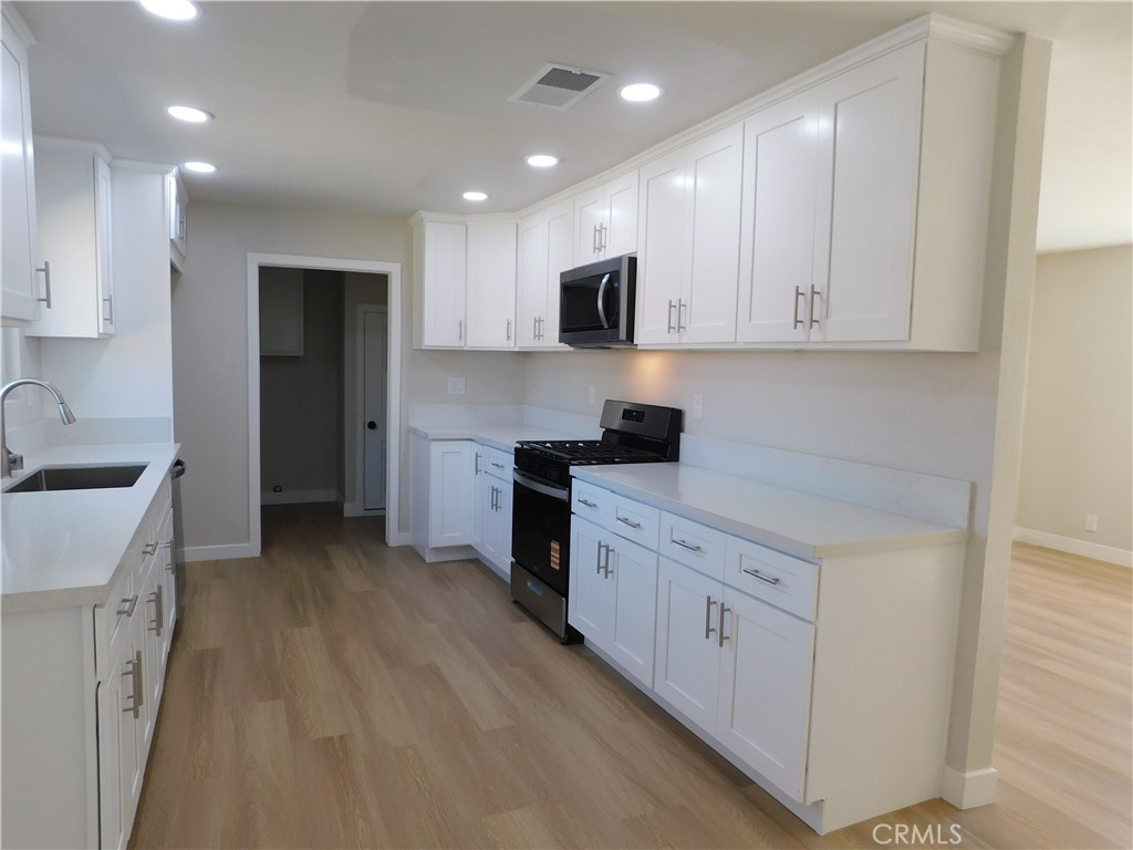 10456 Napa Road Adelanto, CA 92301 - Photo 10 of 31 a kitchen with stainless steel appliances granite countertop a stove a sink and a refrigerator