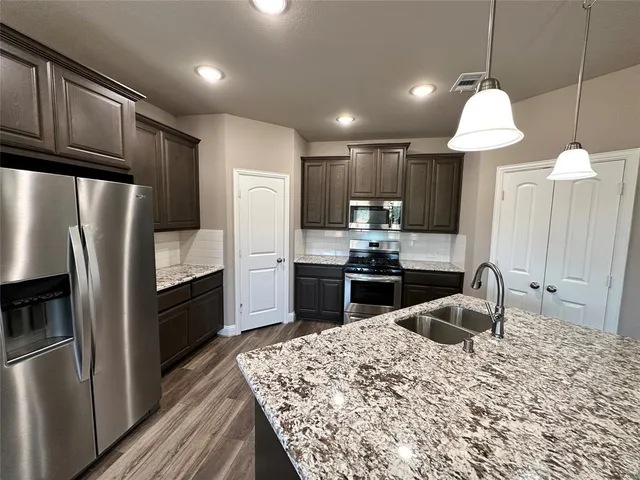 a kitchen with granite countertop a refrigerator and a stove top oven
