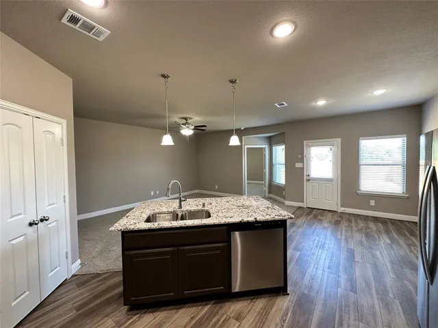 a kitchen with granite countertop kitchen island a sink appliances and a window