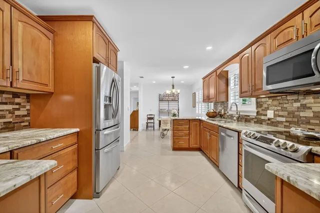 a kitchen with stainless steel appliances granite countertop a stove top oven a sink dishwasher and a refrigerator