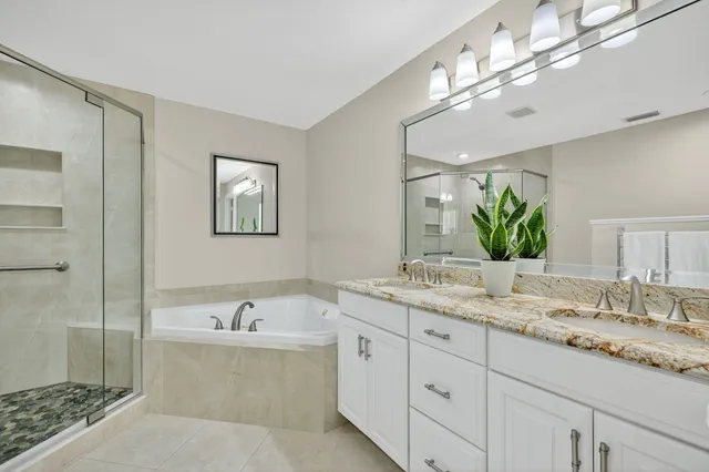a bathroom with a granite countertop double vanity sink and mirror
