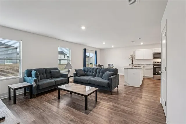 a living room with couches and kitchen view with wooden floor