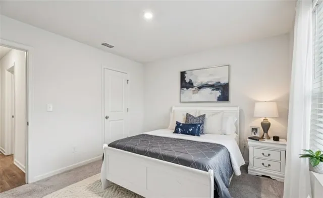 a bedroom with a bed and a lamp on the dresser