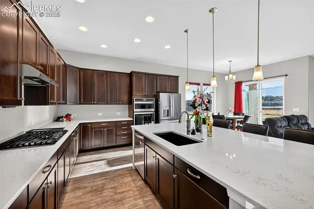 a kitchen with stainless steel appliances a sink a stove cabinets and wooden floor