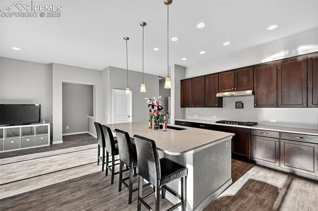 a kitchen with stainless steel appliances granite countertop a kitchen island hardwood floor sink stove dining table and chairs