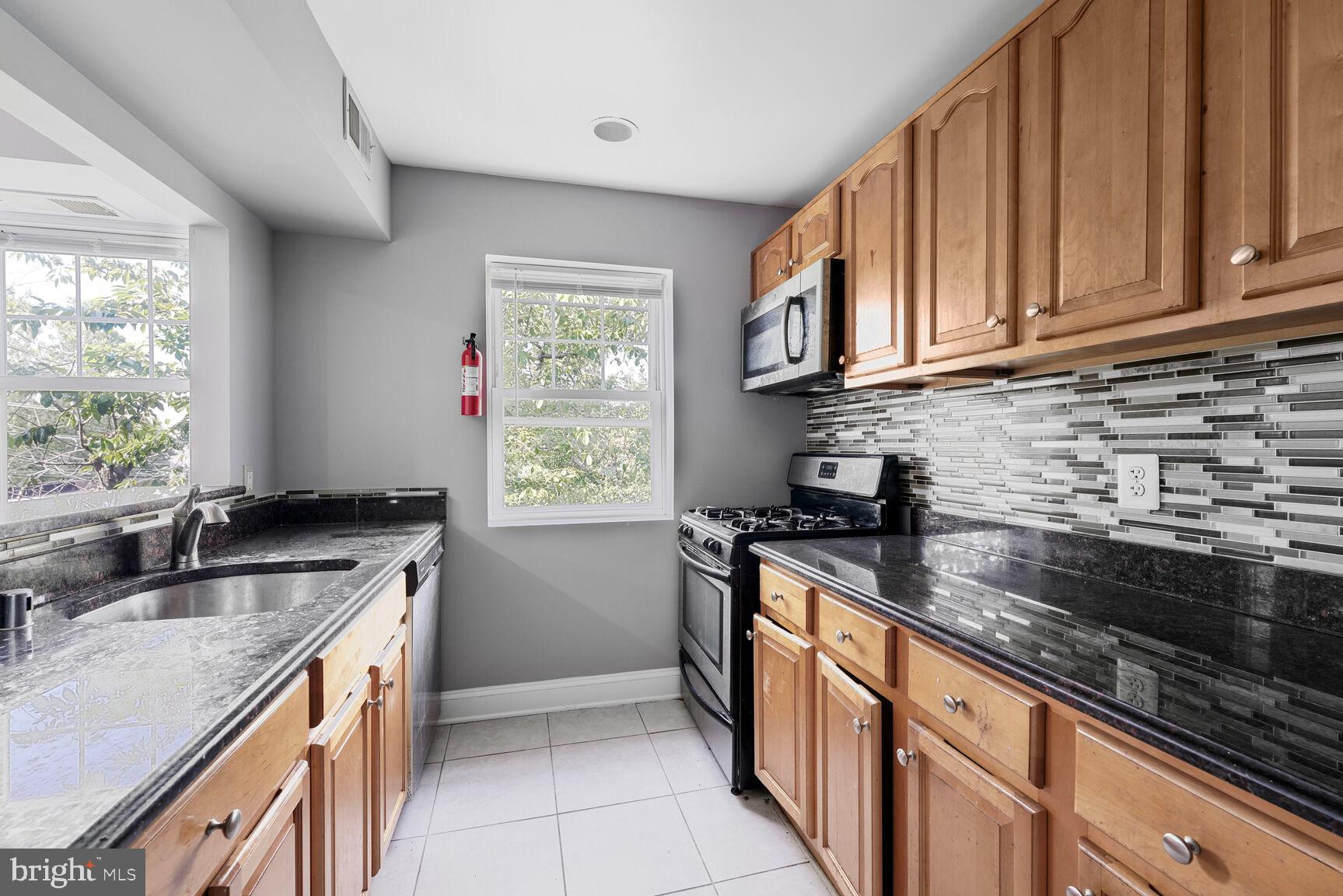 3876 9th Street Southeast, Unit 301 Washington, DC 20032 - Photo 5 of 16 a kitchen with stainless steel appliances granite countertop a sink stove and cabinets