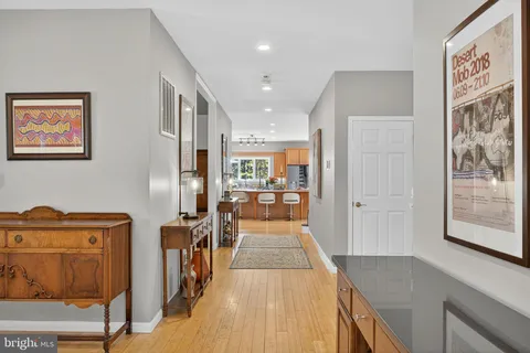 a room with stainless steel appliances kitchen island granite countertop wooden cabinets and a view of living room